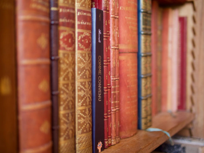 Le livre Comme convenu parmi des livres anciens dans une bibliothèque. Merci Gaétan ! 